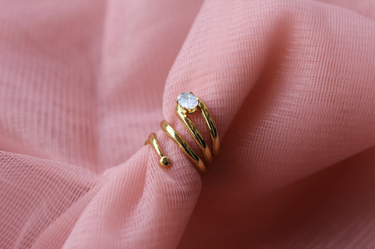 Gold ring with a diamond on a pink fabric background
