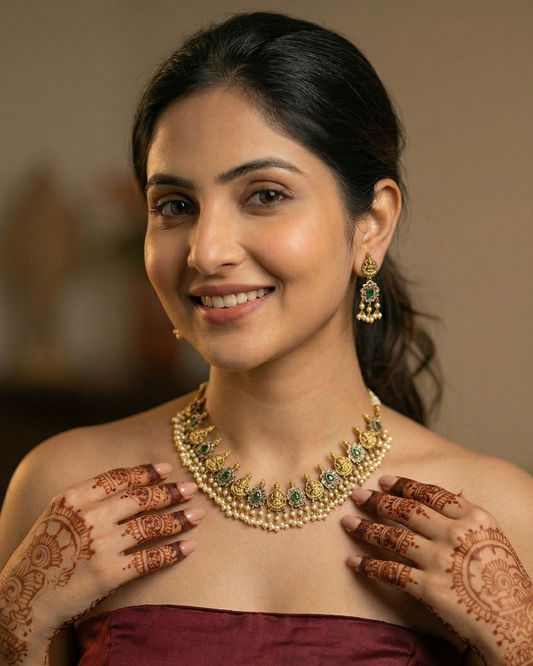 Woman wearing gold jewelry with henna designs on her hands against a blurred background