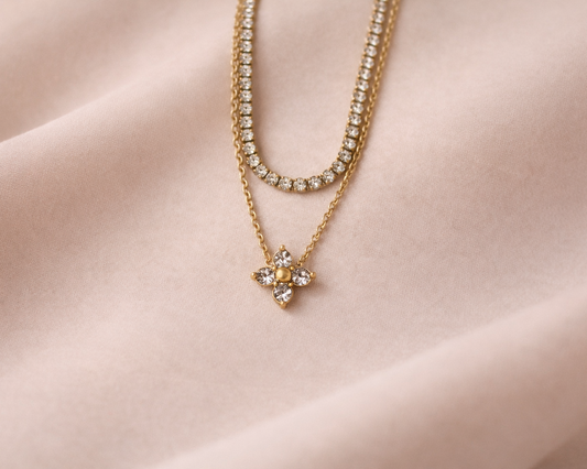 Two gold necklaces with floral pendants on a white background