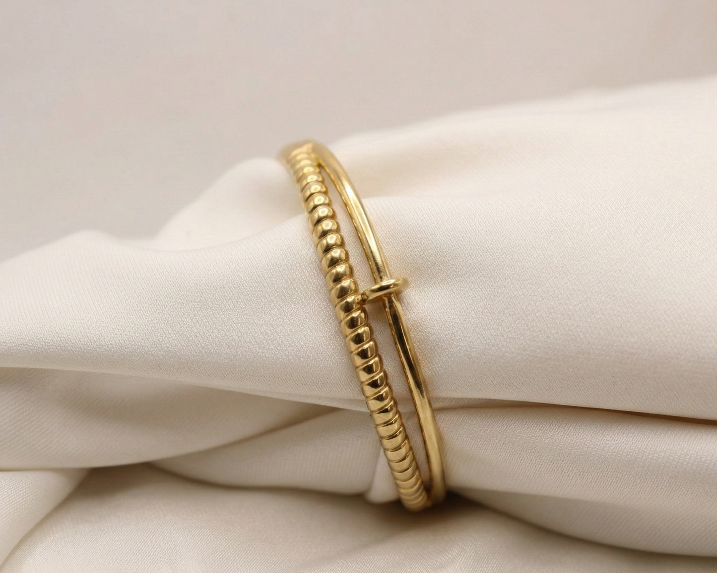 Gold bracelet on a white fabric background