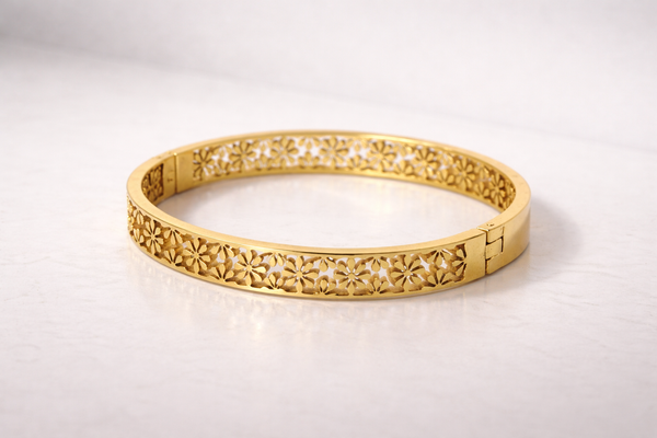 Gold bracelet with intricate design on a light gray background