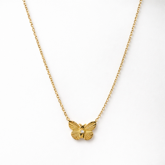 Gold butterfly necklace on a white background