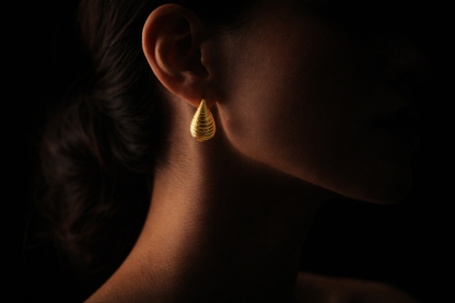 Close-up of a person wearing a gold earring against a dark background