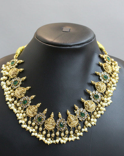Decorative necklace with green stones on a black mannequin bust against a beige background