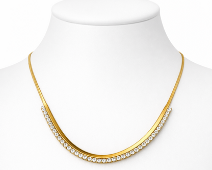 Gold necklace with clear stones on a mannequin bust against a white background