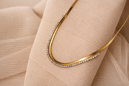 Gold necklace with small diamonds on a beige fabric background
