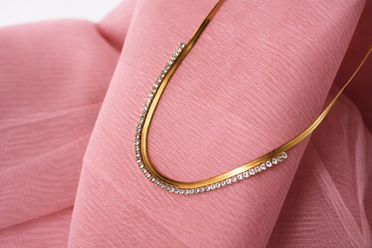 Gold necklace with small diamonds on a pink fabric background