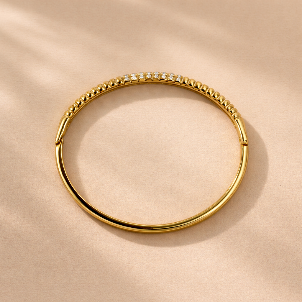 Gold bracelet with embedded stones on a beige background
