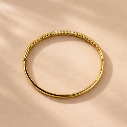 Gold bracelet with embedded stones on a beige background