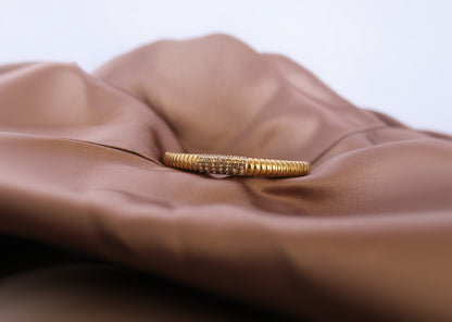 Gold bracelet with embedded stones on a brown fabric background