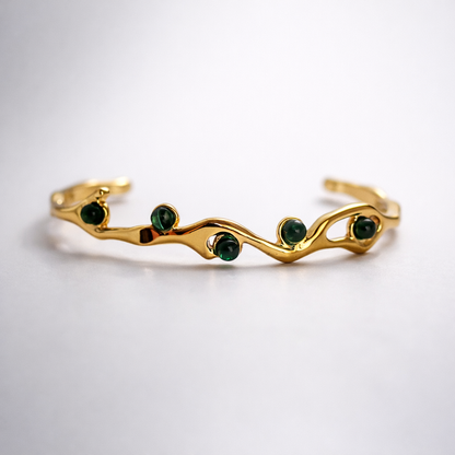 Gold bracelet with green gemstones on a white background