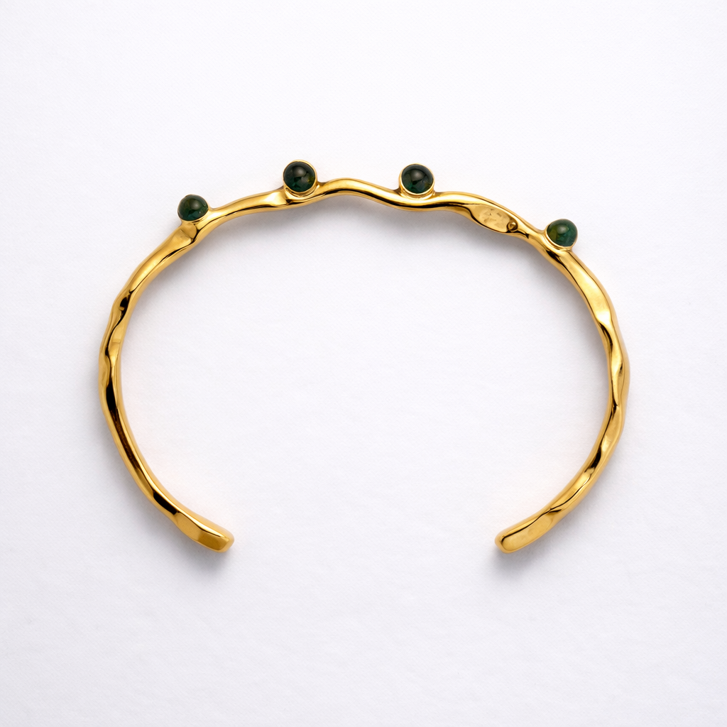 Gold bracelet with green stones on a white background