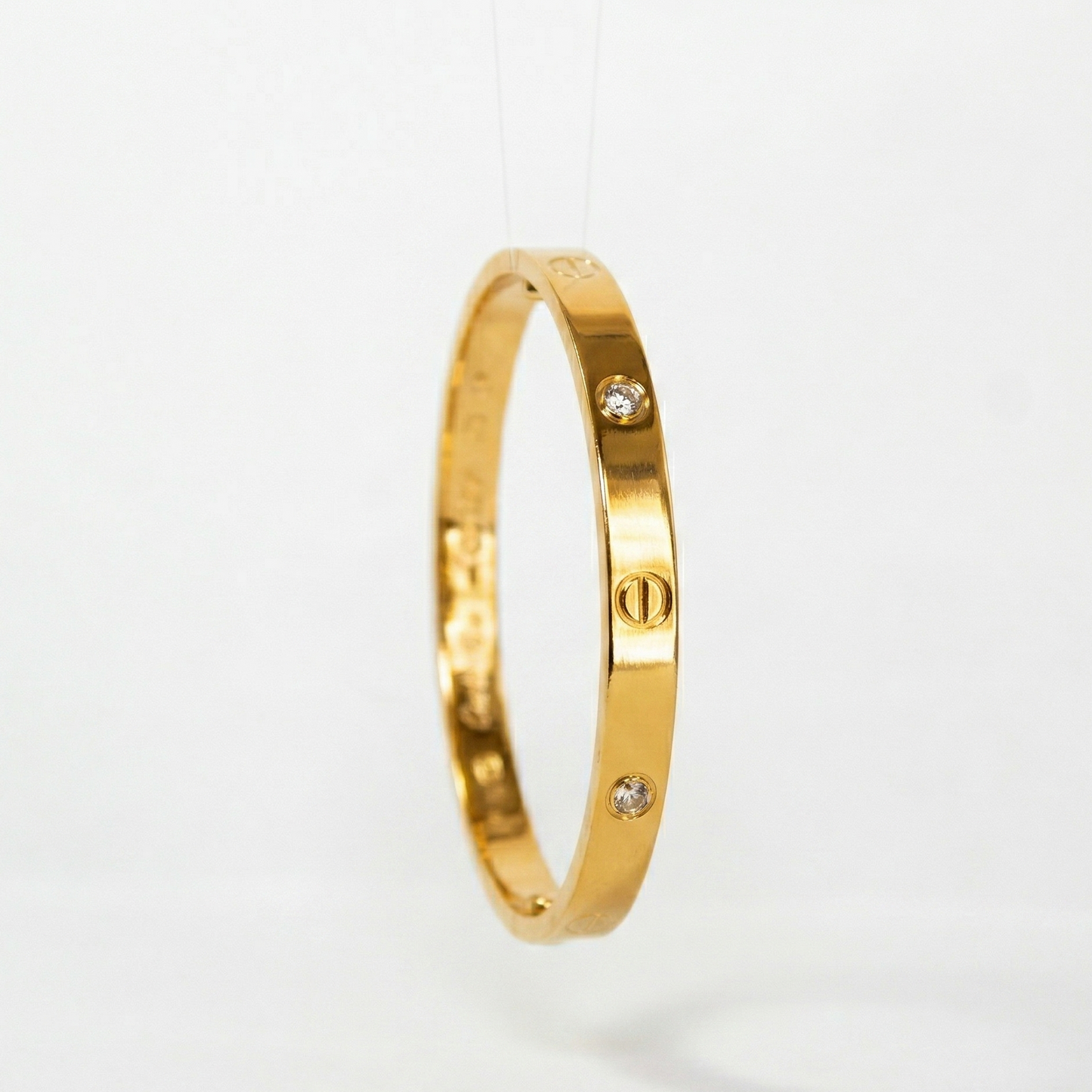 Gold bracelet with small diamonds on a light gray background