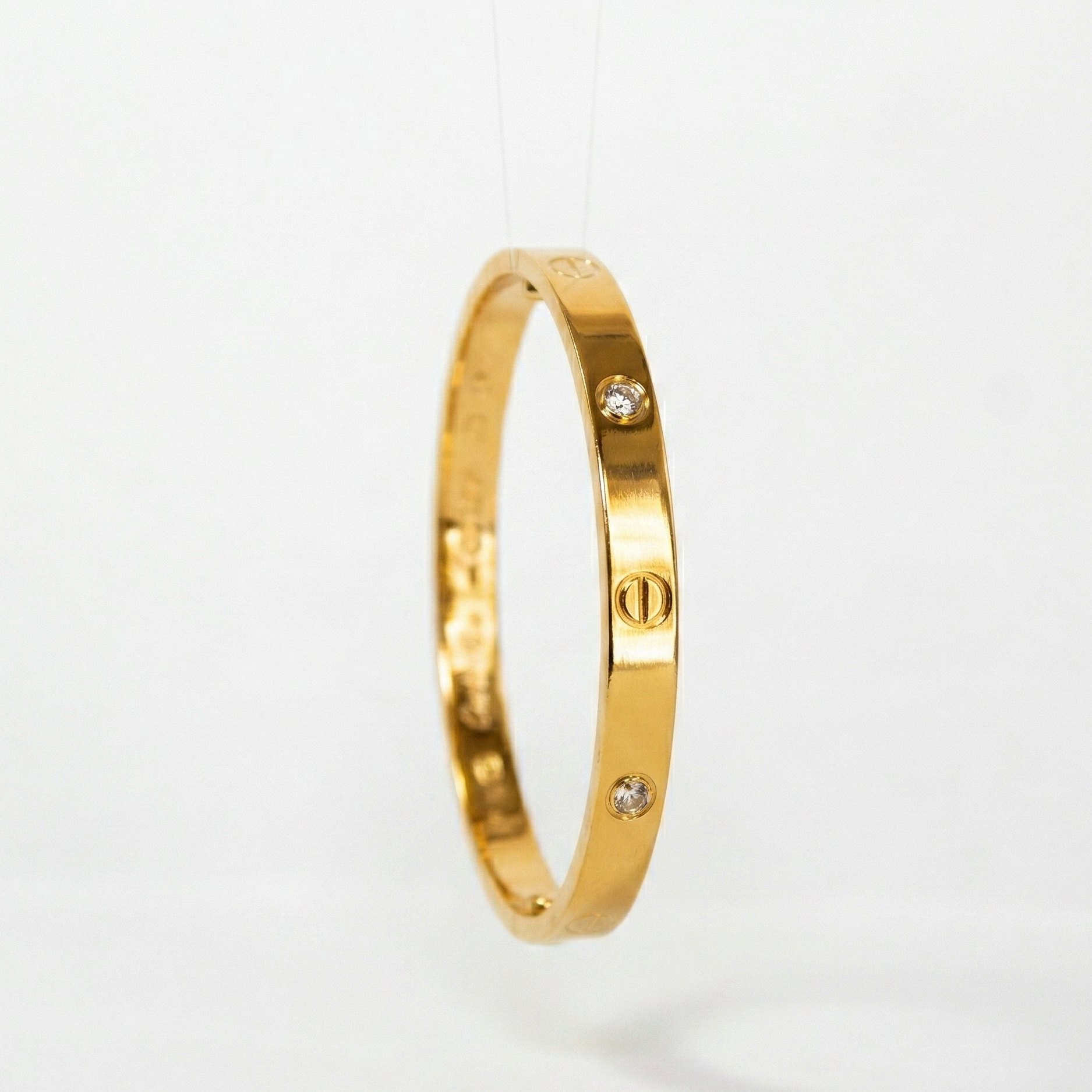 Gold bracelet with small diamonds on a light gray background