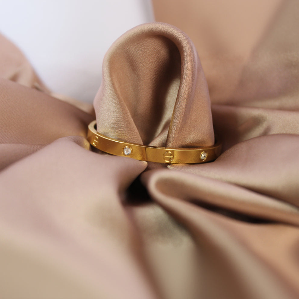 Gold bracelet with small diamonds on a brown fabric background