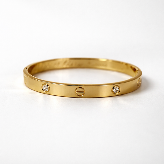 Gold bracelet with three diamond-like stones on a white background