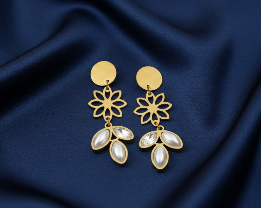 Gold earrings with floral design on a blue satin background