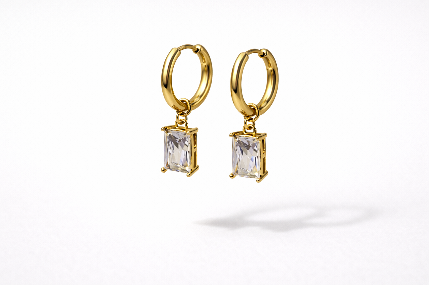 Gold hoop earrings with rectangular gemstones on a white background