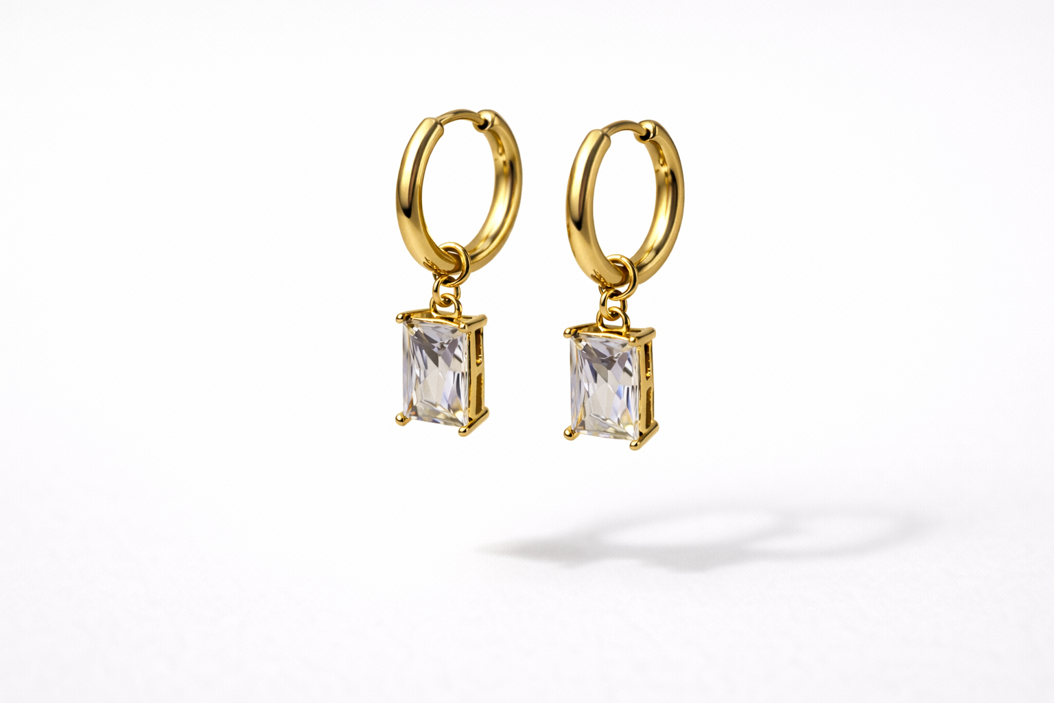 Gold hoop earrings with rectangular gemstones on a white background