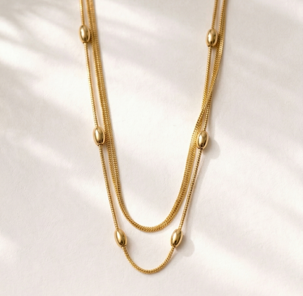 Gold necklace on a white shell background