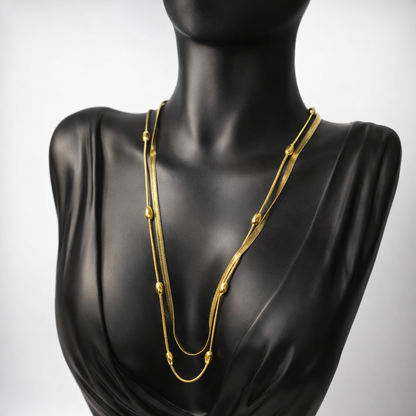 Gold necklace on a black mannequin against a gray background