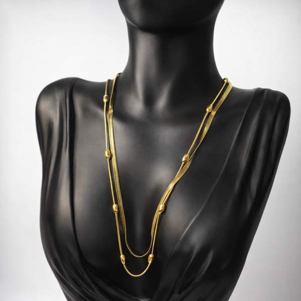 Gold necklace on a black mannequin against a gray background