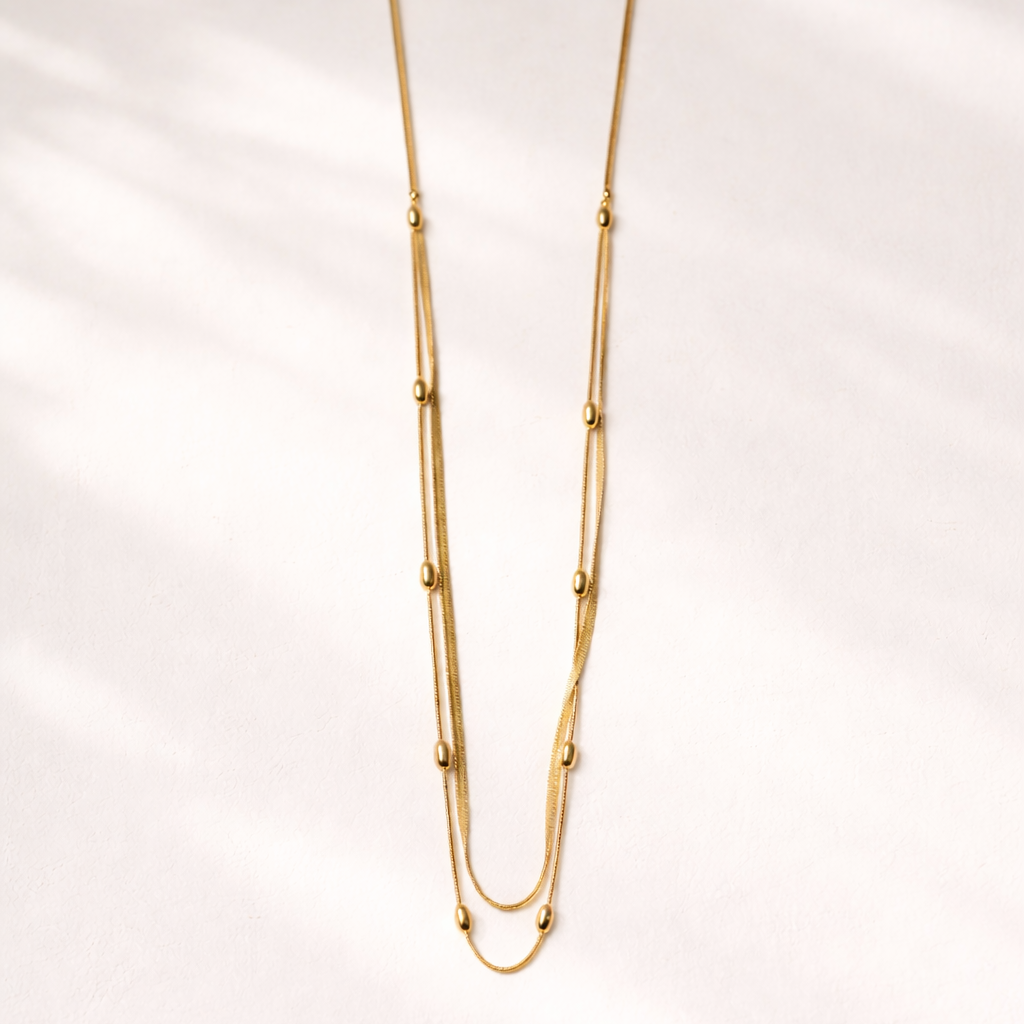 Gold necklace on a light pink background