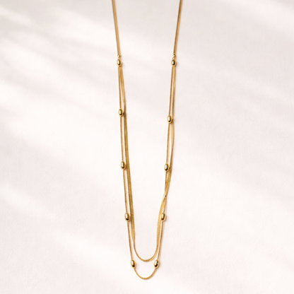 Gold necklace on a light pink background