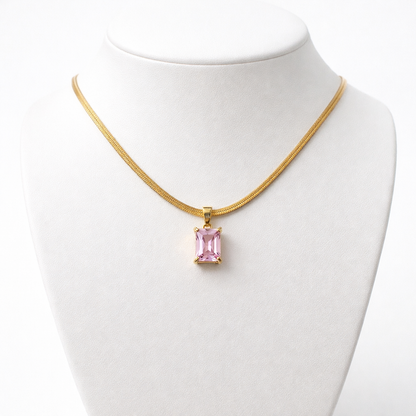 Gold necklace with a pink pendant on a mannequin bust against a white background