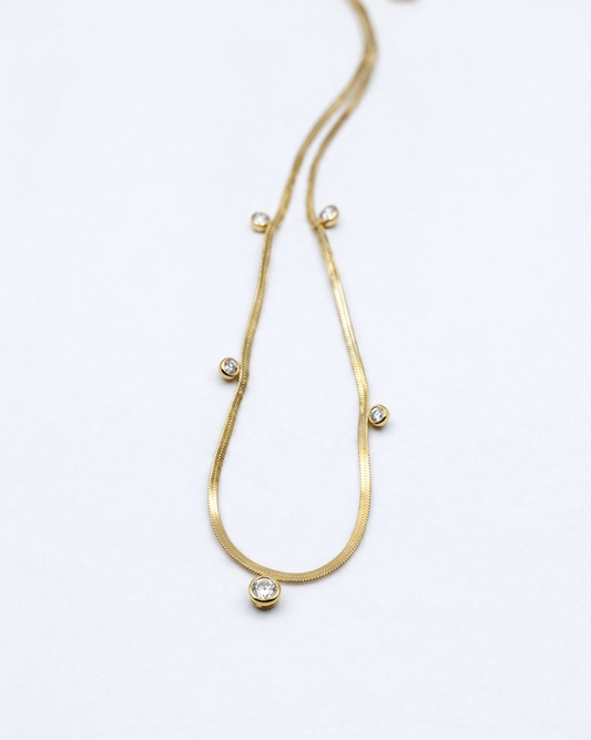 Gold necklace with small beads on a white background