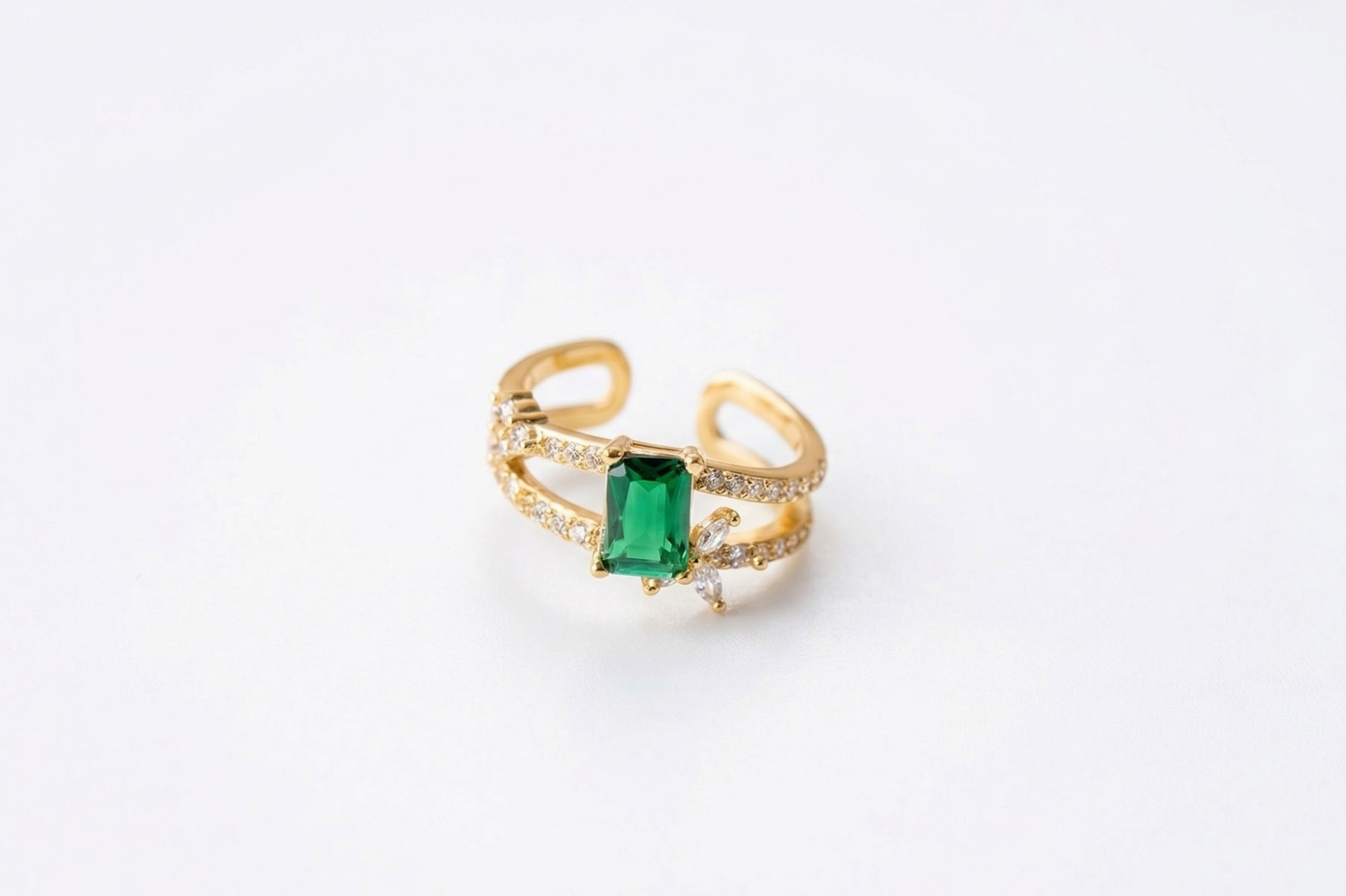 Gold ring with a green gemstone on a white background