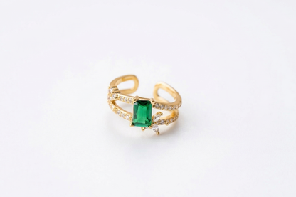 Gold ring with a green gemstone on a white background