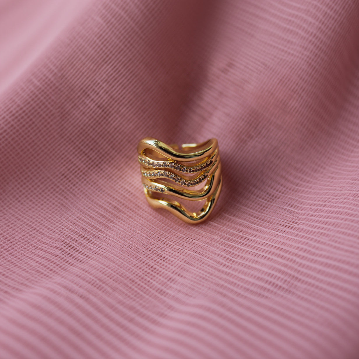Gold ring with diamond accents on a PINK background