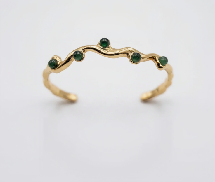 Gold ring with green gemstones on a white background