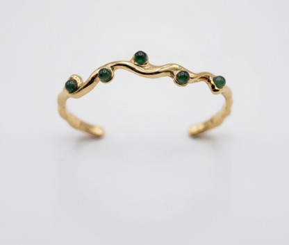 Gold ring with green gemstones on a white background