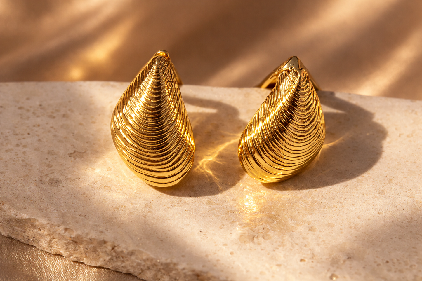 Pair of gold earrings on a marble surface with a soft background
