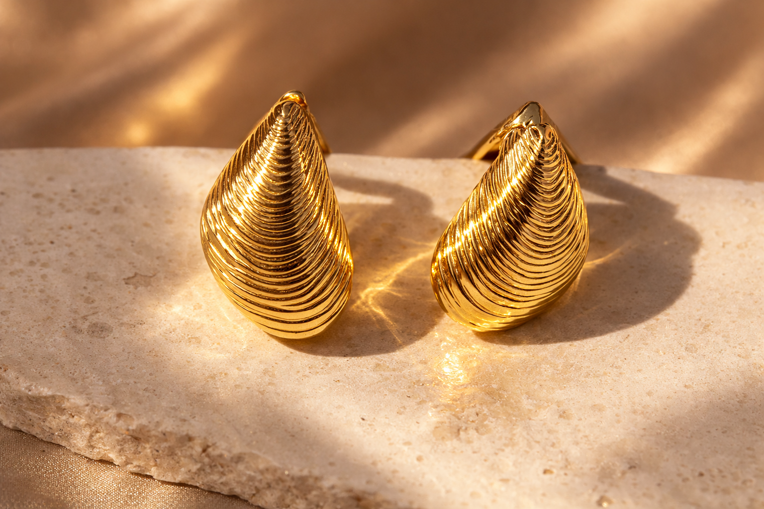 Pair of gold earrings on a marble surface with a soft background