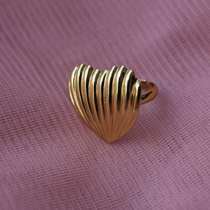 Gold shell-shaped ring on a pink fabric background