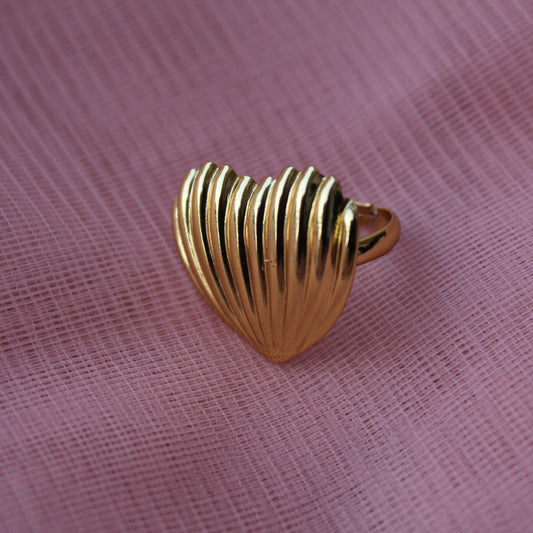 Gold shell-shaped ring on a pink fabric background