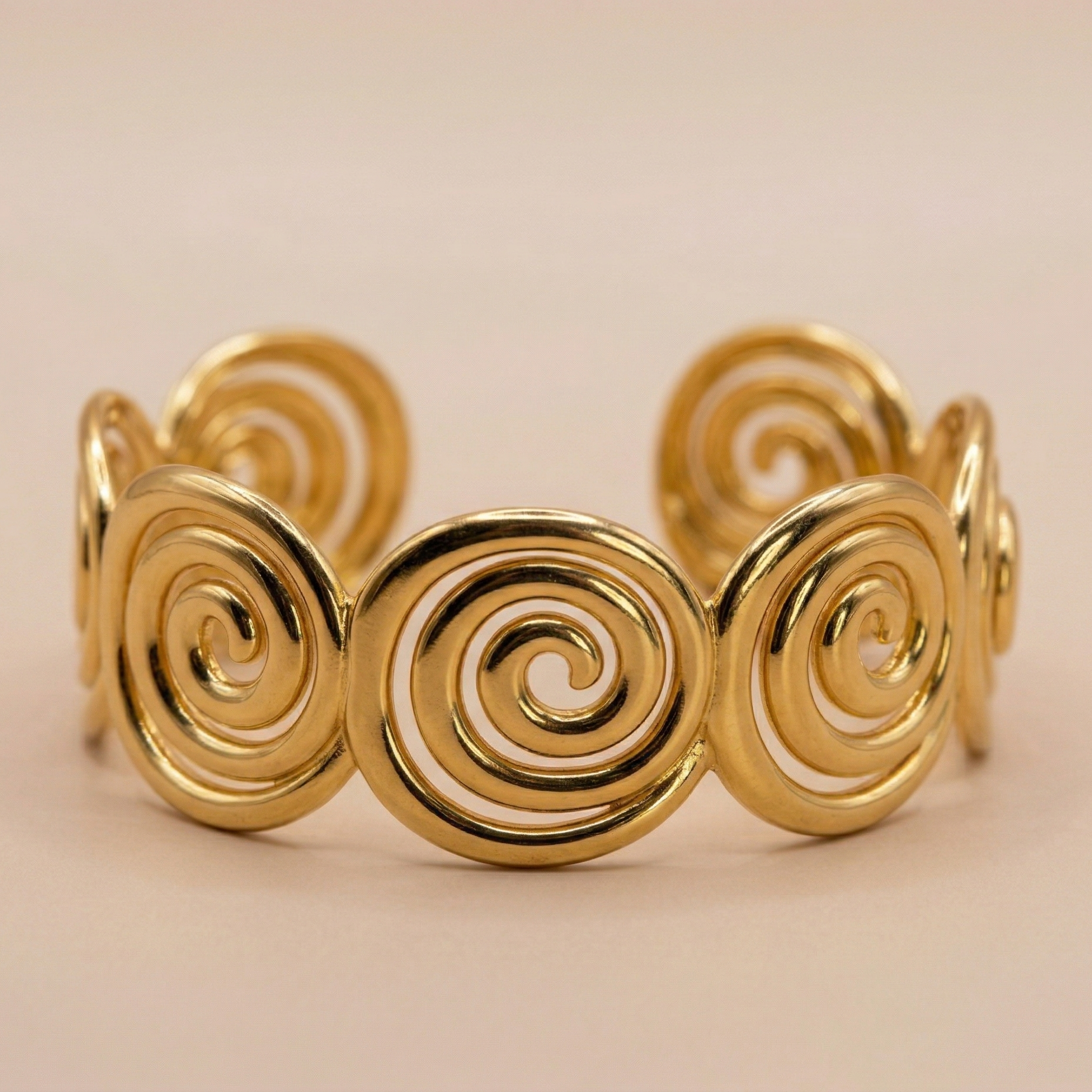 Gold spiral bracelet on a beige background