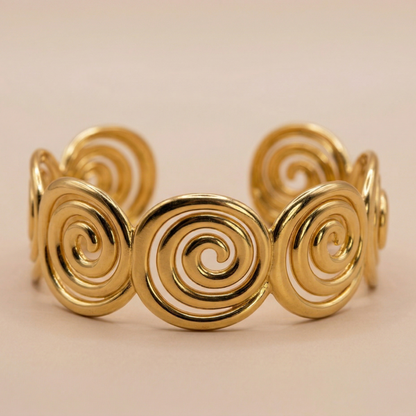 Gold spiral bracelet on a beige background