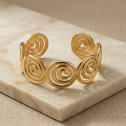 Gold spiral bracelet on a marble surface