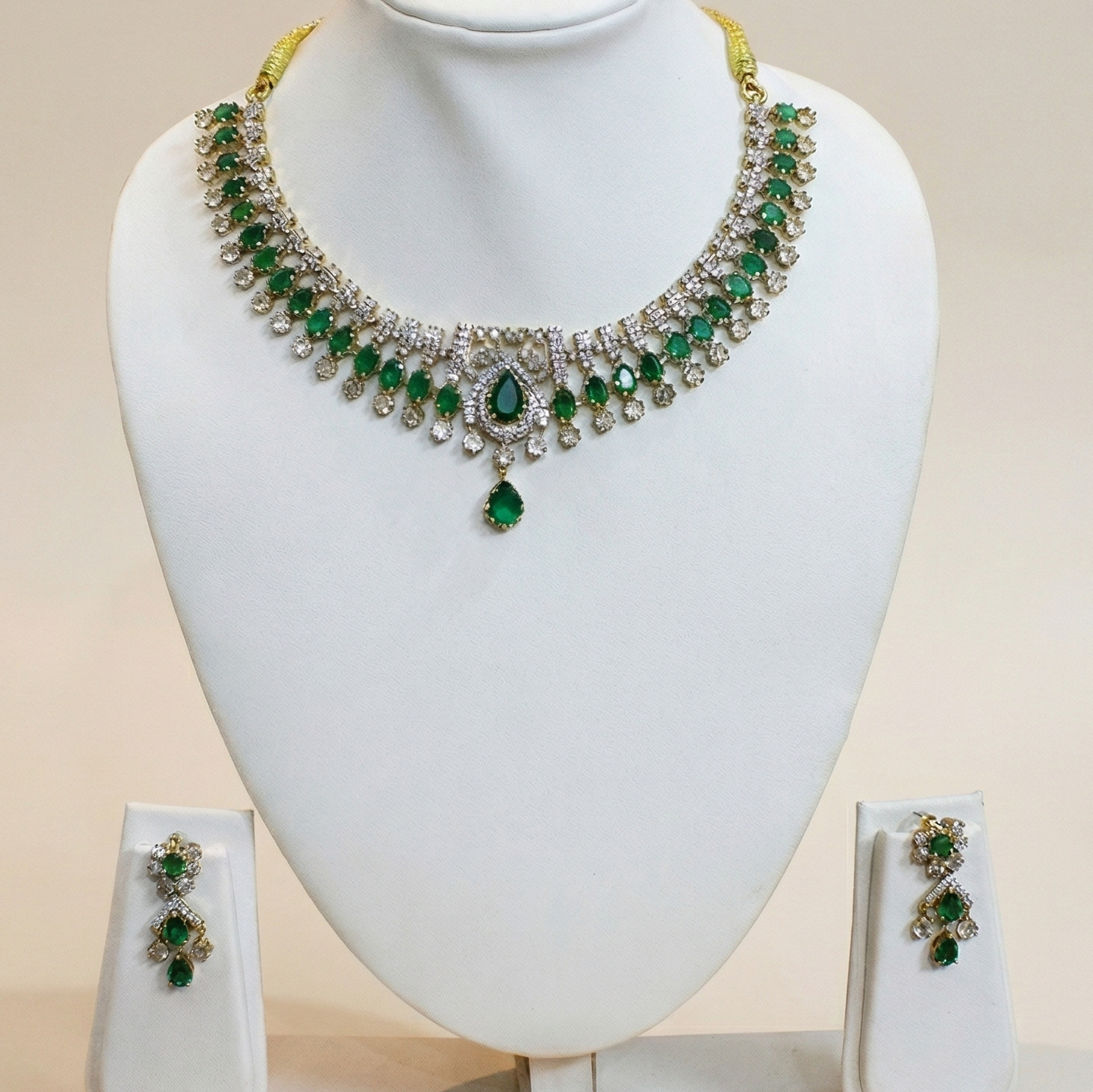 Green gemstone necklace and earrings on a white mannequin bust with a beige background