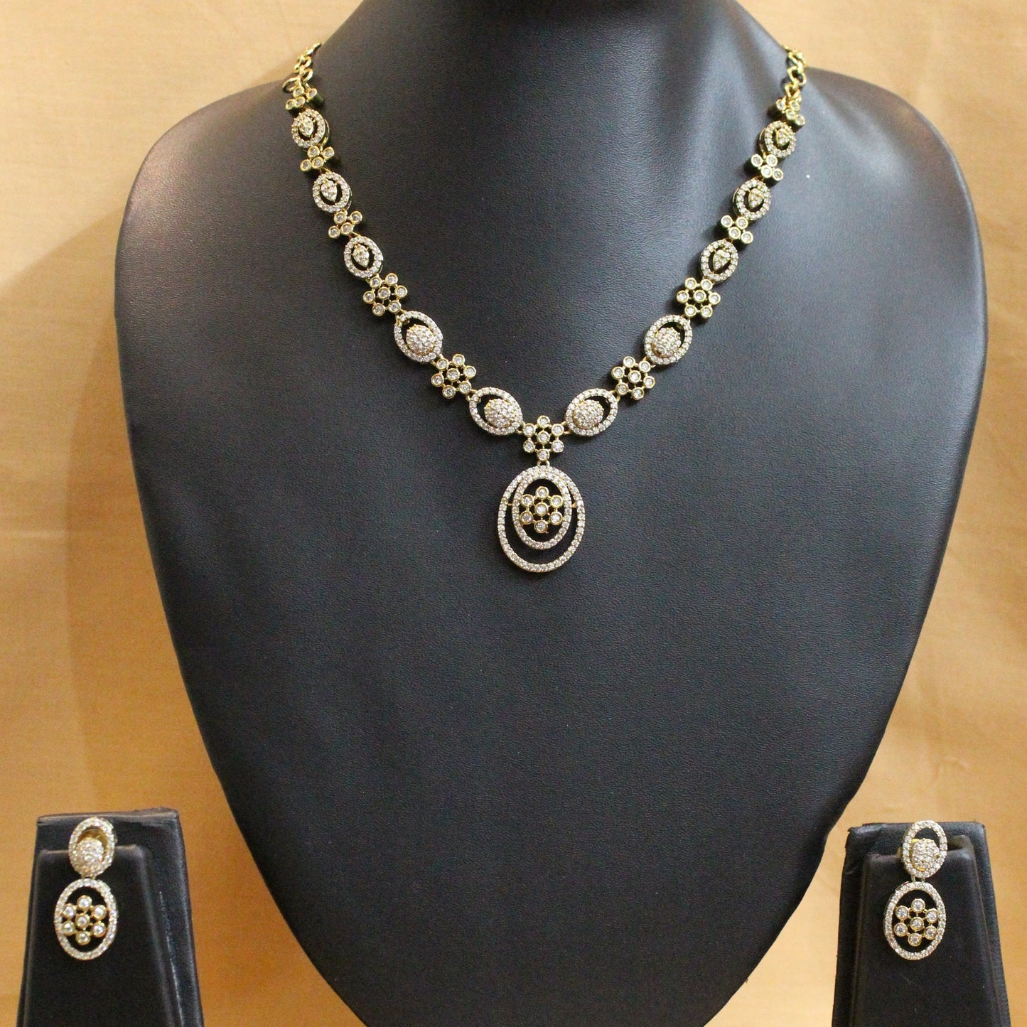 Gold necklace on a black mannequin bust against a beige background