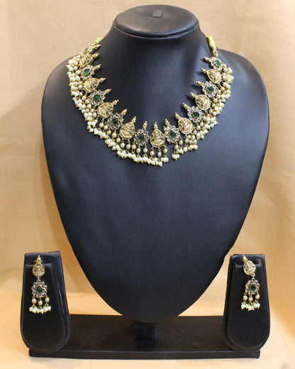 Jewelry set with necklace and earrings on a black stand against a beige curtain.