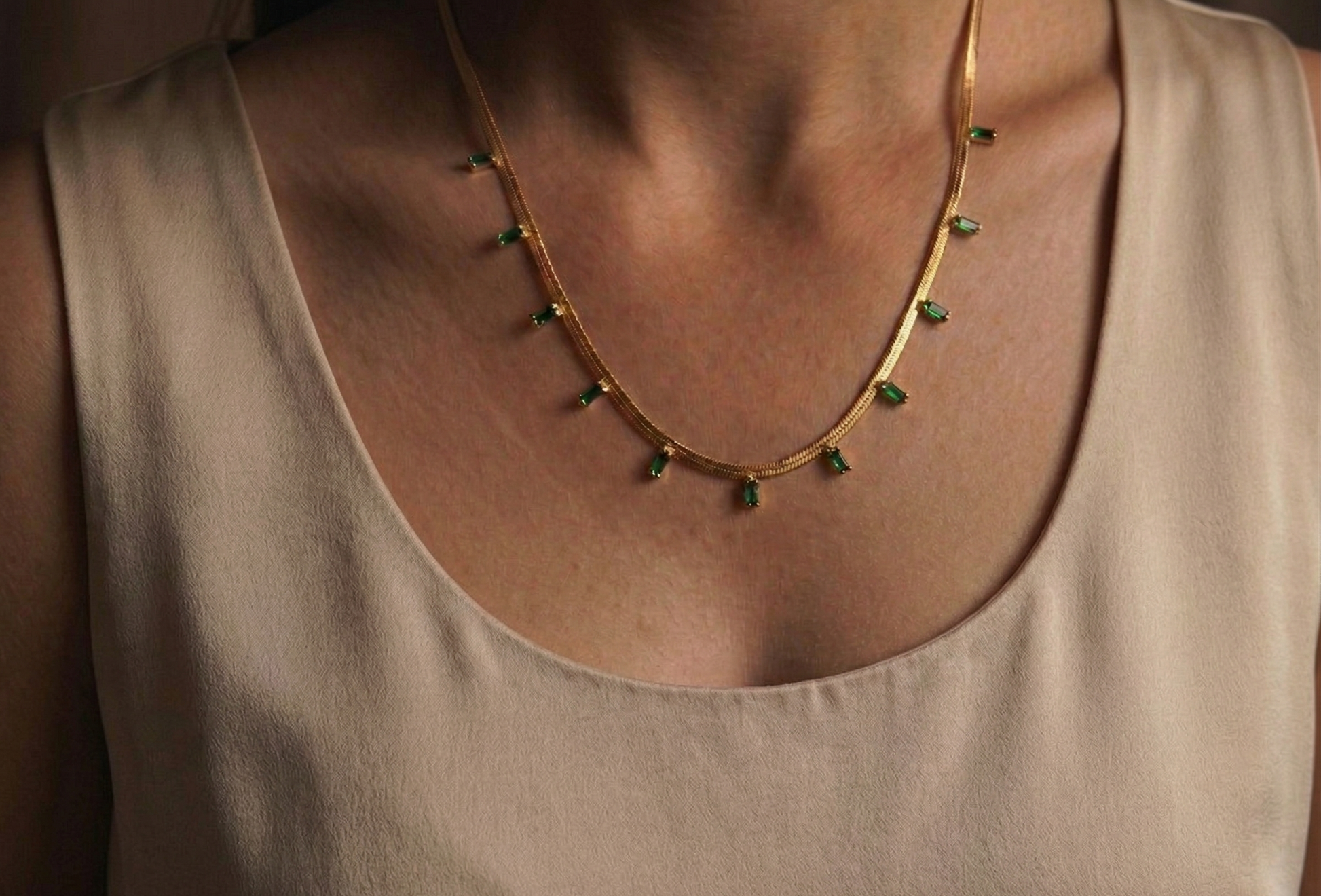Necklace with green gemstones on a beige top