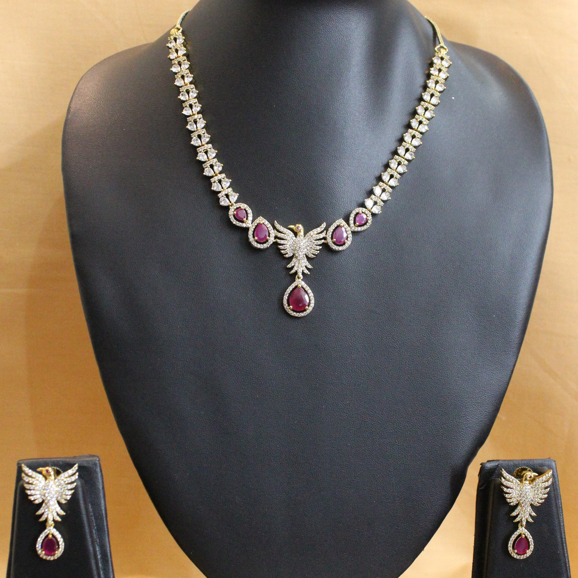 Jewelry set with necklace and earrings on a black mannequin bust against a beige background