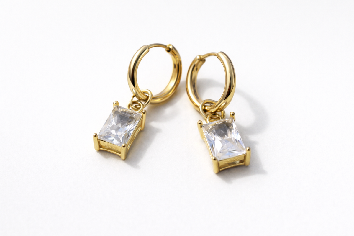 Gold hoop earrings with clear gemstones on a white background