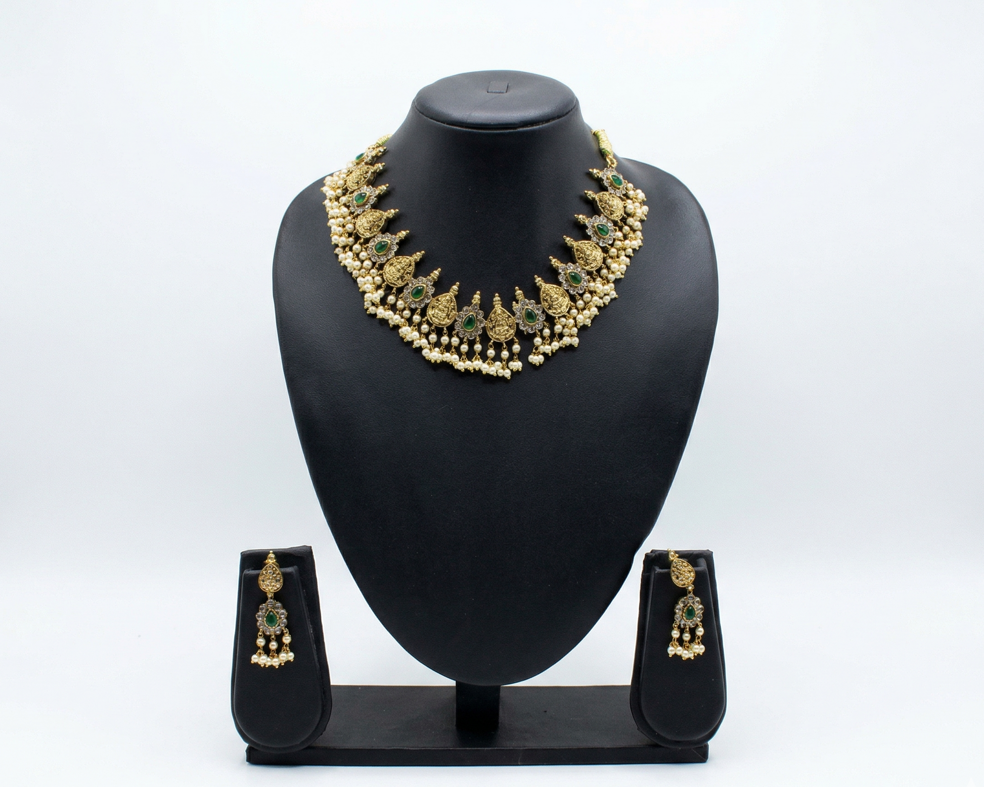 Gold necklace and earrings set on a black mannequin bust against a white background