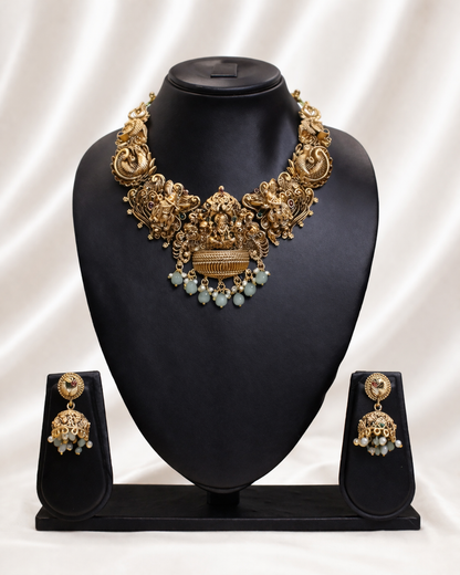Gold necklace and earrings set on a black mannequin bust with a white background